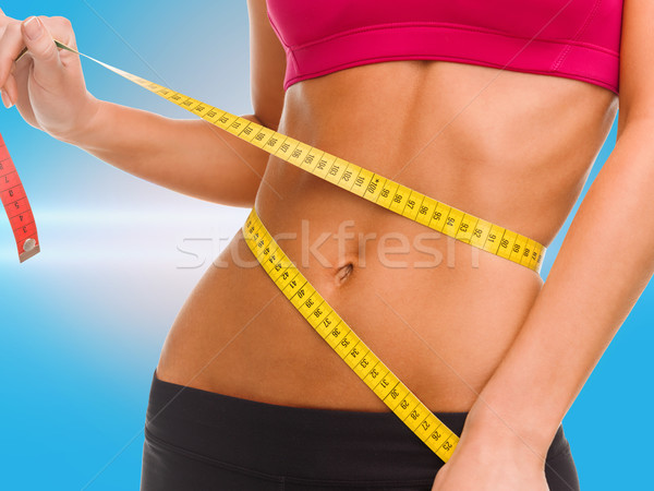 close up of trained belly with measuring tape Stock photo © dolgachov