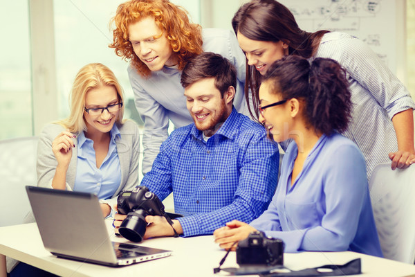 smiling team with laptop and photocamera in office Stock photo © dolgachov