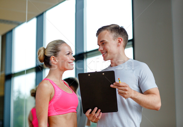 smiling young woman with personal trainer in gym Stock photo © dolgachov