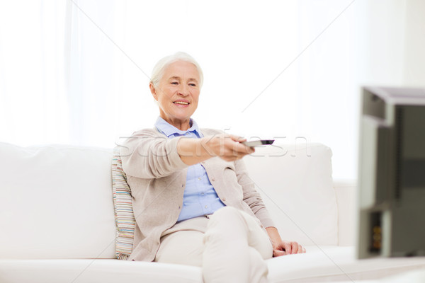 happy senior woman watching tv at home Stock photo © dolgachov