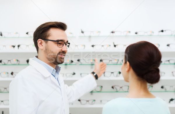 woman and optician showing glasses at optics store Stock photo © dolgachov