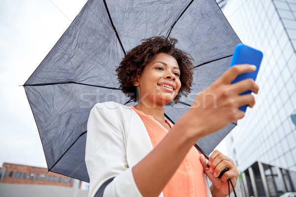 businesswoman with umbrella texting on smartphone Stock photo © dolgachov