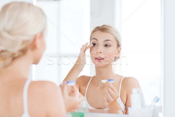 young woman putting on contact lenses at bathroom Stock photo © dolgachov