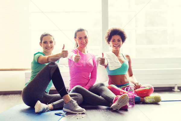 happy women with water showing thumbs up in gym Stock photo © dolgachov
