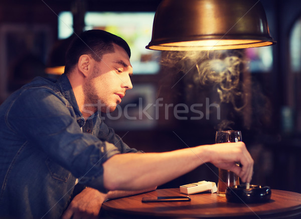man drinking beer and smoking cigarette at bar Stock photo © dolgachov