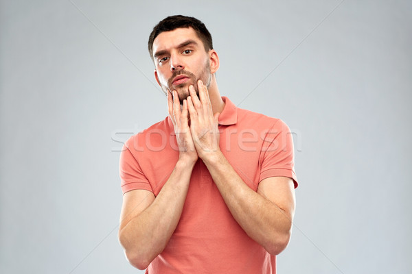 young man touching his face over gray background Stock photo © dolgachov