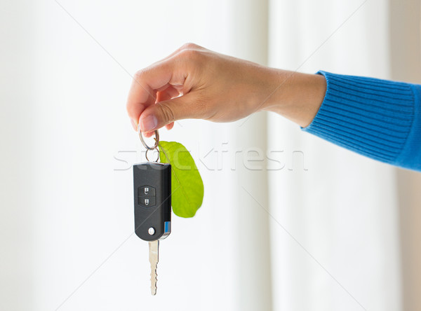 Stock photo: close up of hand holding car key with green leaf