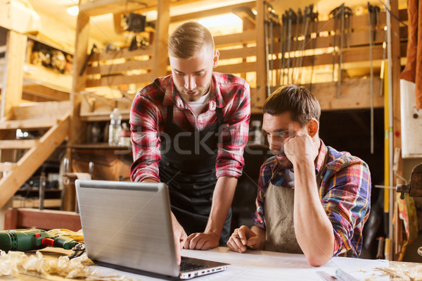 carpenters with laptop and blueprint at workshop Stock photo © dolgachov
