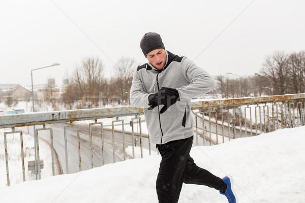 man with earphones running along winter bridge Stock photo © dolgachov