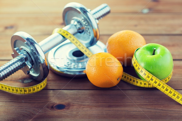 close up of dumbbell, fruits and measuring tape Stock photo © dolgachov