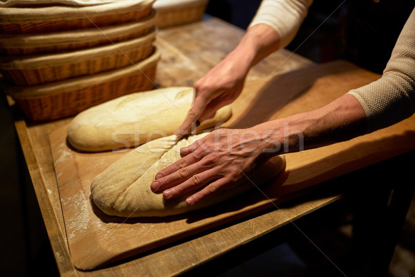baker making bread and cutting dough at bakery Stock photo © dolgachov
