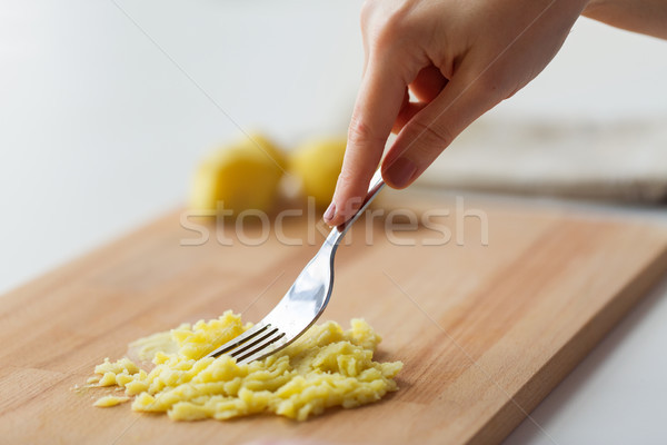 hand with fork making mashed potato on board Stock photo © dolgachov