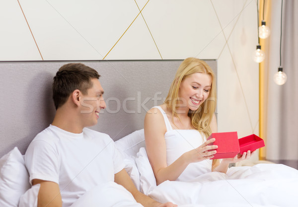 smiling couple in bed with red gift box Stock photo © dolgachov