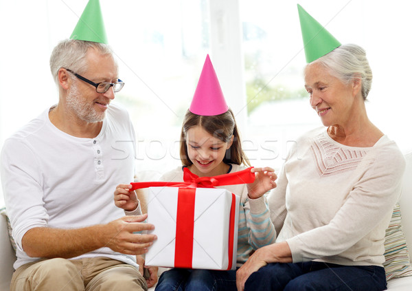 smiling family in party hats with gift box at home Stock photo © dolgachov