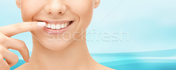 close up of smiling woman face pointing to teeth Stock photo © dolgachov