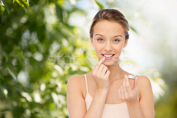 Souriant jeune femme lèvre baume lèvres Photo stock © dolgachov