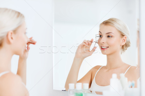 woman with curler curling eyelashes at bathroom Stock photo © dolgachov