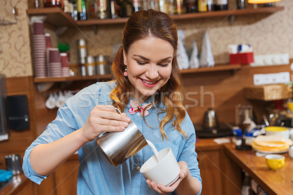 barista woman pouring cream to cup at coffee shop Stock photo © dolgachov