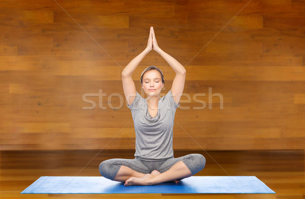 woman making yoga meditation in lotus pose on mat Stock photo © dolgachov