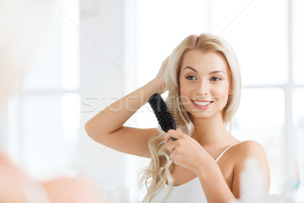 happy woman brushing hair with comb at bathroom Stock photo © dolgachov