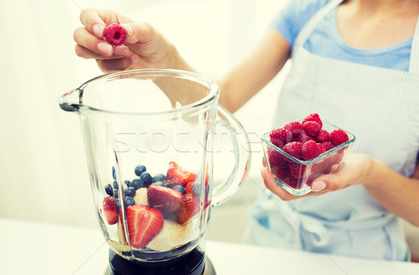 Stock photo: close up of woman with blender making fruit shake