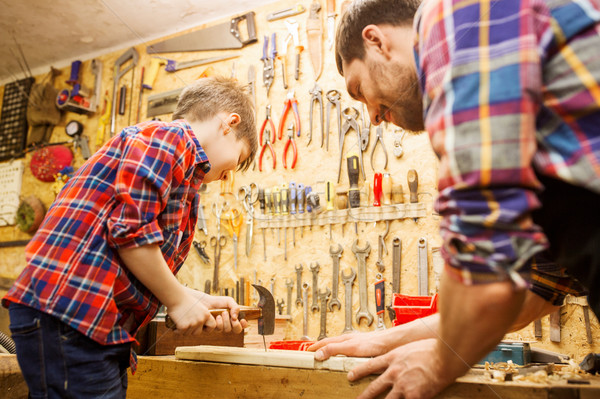 father and son with hammer working at workshop Stock photo © dolgachov