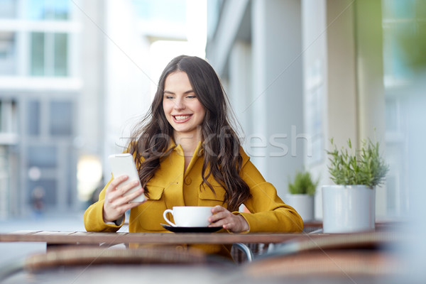 Stock photo: happy woman texting on smartphone at city cafe