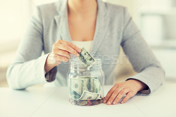 Stock photo: close up of woman hands and dollar money in jar