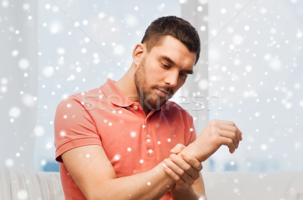 unhappy man suffering from pain in hand at home Stock photo © dolgachov