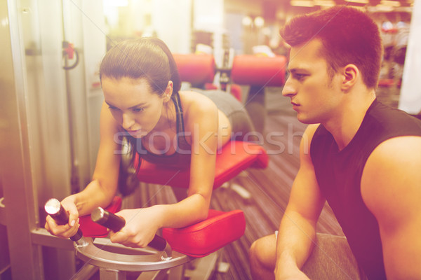 young woman with trainer exercising on gym machine Stock photo © dolgachov