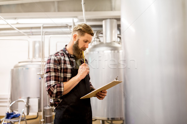man with clipboard at craft brewery or beer plant Stock photo © dolgachov