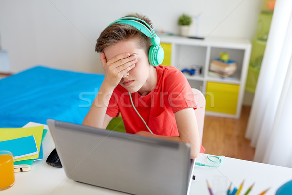 Stock photo: boy in headphones playing video game on laptop