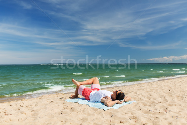 happy smiling young man sunbathing on beach towel Stock photo © dolgachov