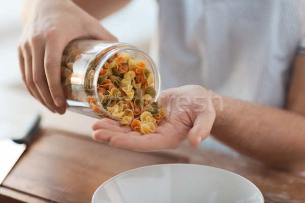 close up of male emptying jar with colorful pasta Stock photo © dolgachov