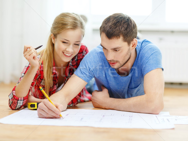 Stock photo: smiling couple looking at blueprint at home