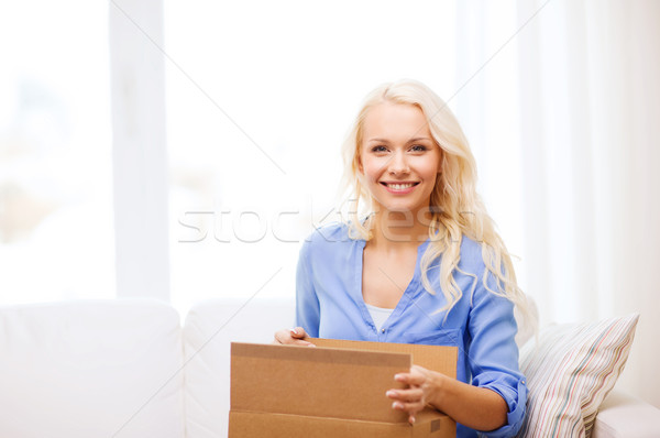 smiling young woman opening cardboard box Stock photo © dolgachov
