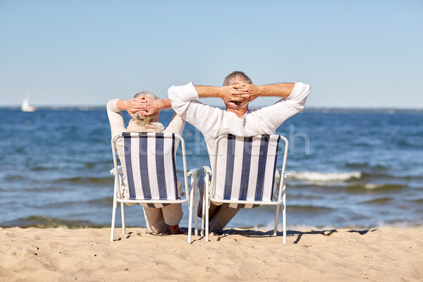 senior couple sitting on chairs at summer beach Stock photo © dolgachov