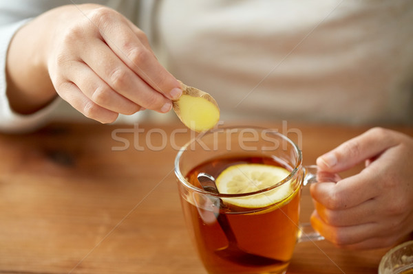 close up of woman adding ginger to tea with lemon Stock photo © dolgachov