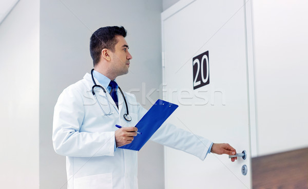 Stock photo: doctor with clipboard opening hospital ward door