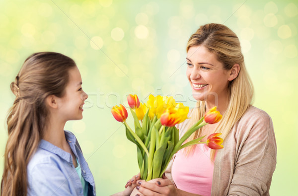 happy girl giving flowers to mother over lights Stock photo © dolgachov