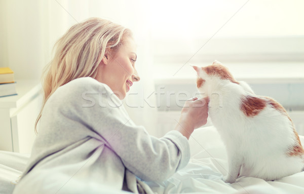 Stock photo: happy young woman with cat in bed at home
