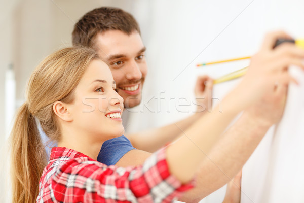 smiling couple measuring wall Stock photo © dolgachov