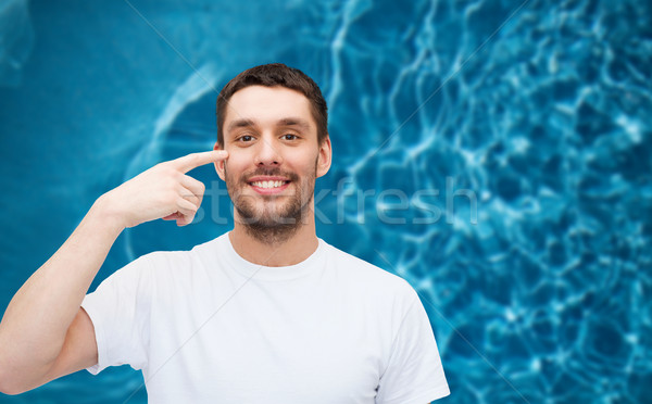smiling young handsome man pointing to eyes Stock photo © dolgachov