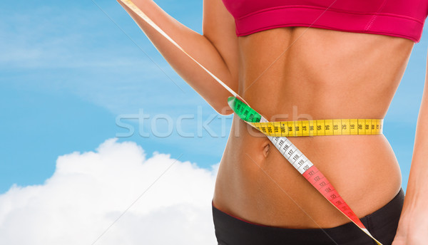 Stock photo: close up of trained belly with measuring tape