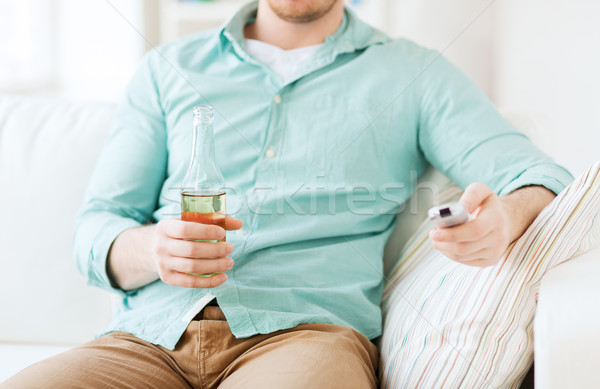 man with beer and remote control at home Stock photo © dolgachov