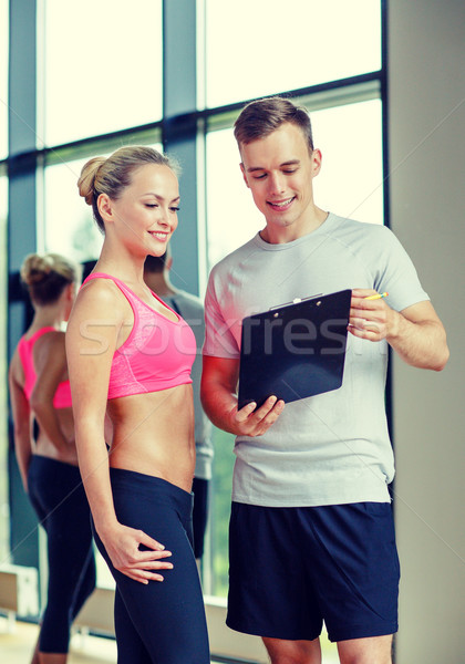 smiling young woman with personal trainer in gym Stock photo © dolgachov