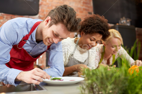 happy friends cooking and decorating dishes Stock photo © dolgachov