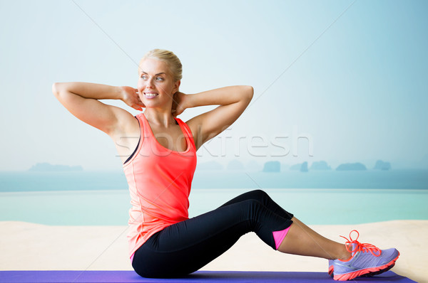 smiling woman doing sit-up on mat over pool Stock photo © dolgachov