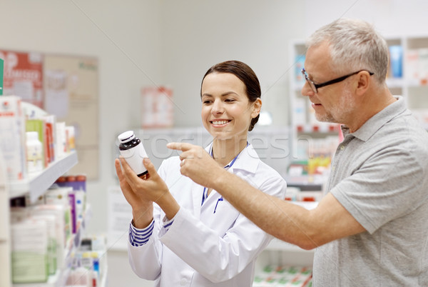 Stock photo: pharmacist showing drug to senior man at pharmacy