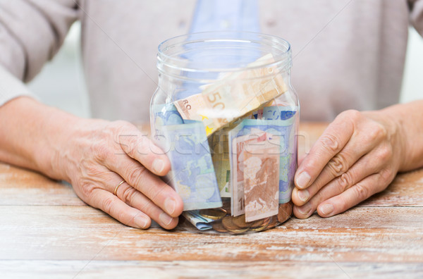 close up of senior woman with money in glass jar Stock photo © dolgachov
